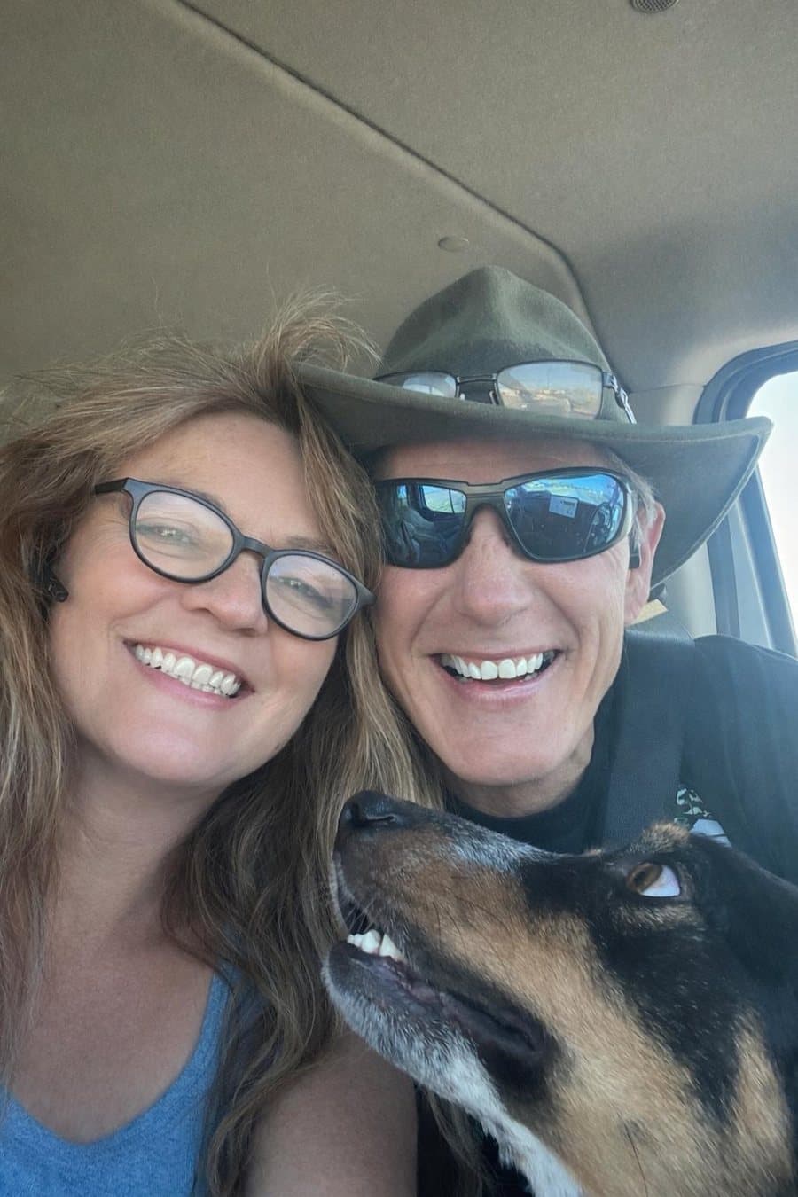 Judi and Jim of Paws Across America Transport in the cab of their van, with a shepherd riding between them