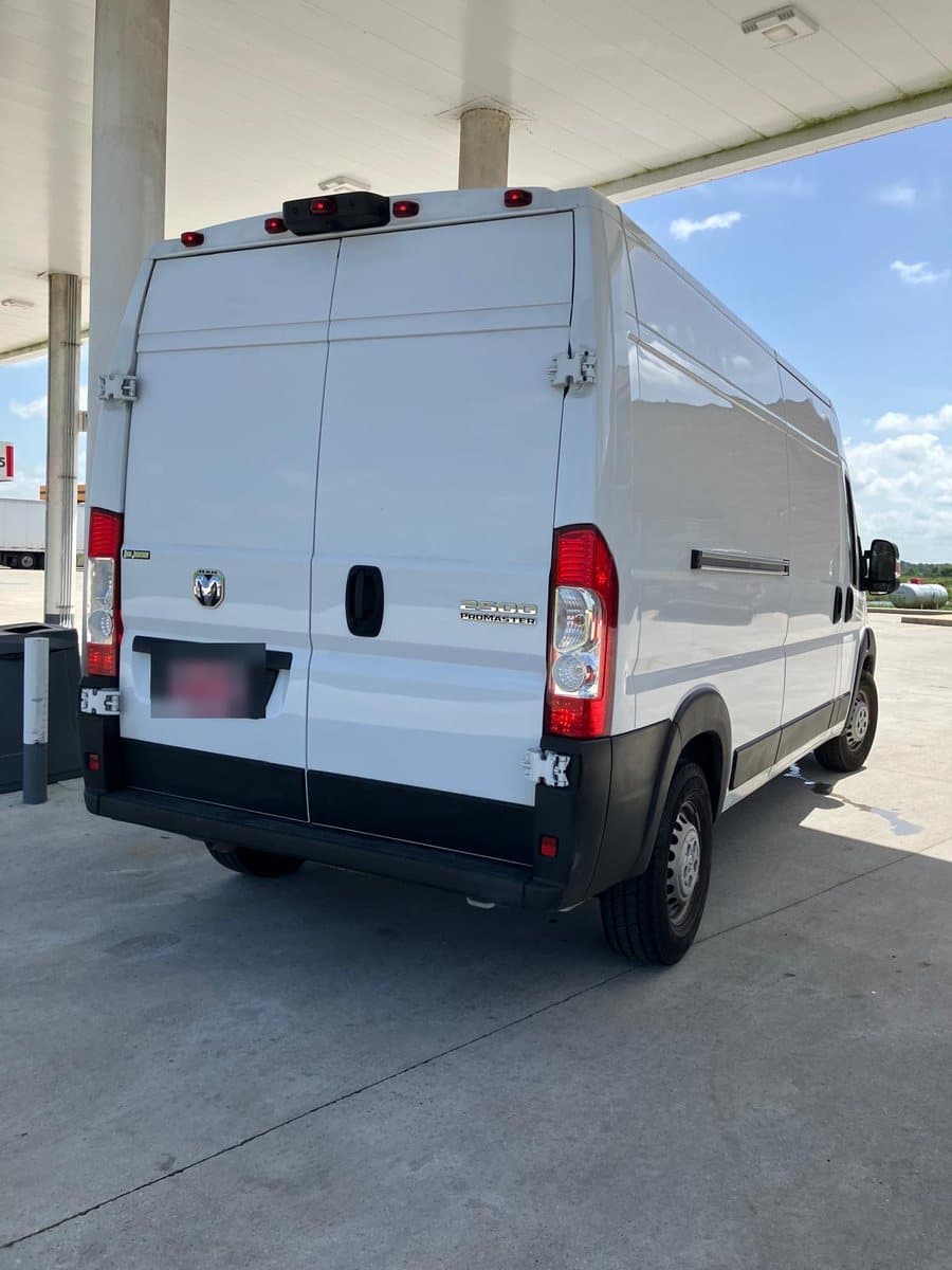 The white high-roof Ram ProMaster 2500 cargo van used by Paws Across America Transport, parked under a fuel canopy